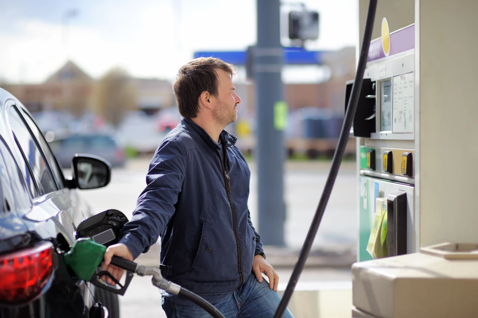 Middle age man filling gasoline fuel in car holding nozzle